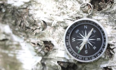Pusula ile turizmin sembolü olarak doğal arka planda klasik navigasyon pusulası, pusula ile seyahat ve pusula ile açık hava aktiviteleri