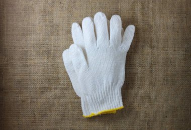 Beyaz kumaş örülmüş eldivenler kahverengi kumaş arkaplanda eski bir çuval bezi.