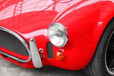 Eski kırmızı arabanın ön tarafı yuvarlak araba farlarıyla çevrili.