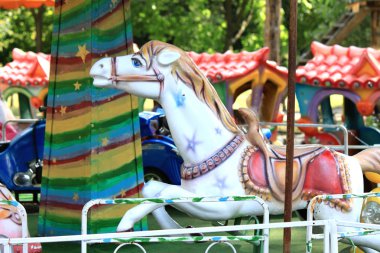 Güzel beyaz atı ile bir tatil parkta eski atlıkarınca