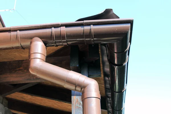 Brown rain gutter on a home against blue sky — Stock Photo, Image