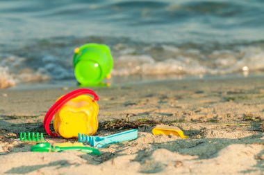 Oyuncak kovalar ve diğer oyuncaklar dalgalar kenarına yakın bir plajda