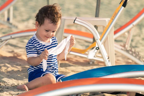 Toddler dressed as a sailor playing with his clothes near sunbed — Stock Photo, Image