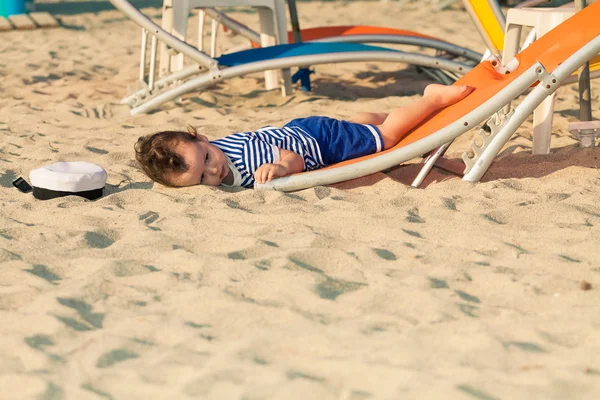 Småbarn klädd som en sjöman liggande från en början i en solstol på en vara — Stockfoto