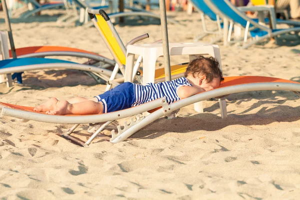 Småbarn klädd som en sjöman liggande på en solstol på en strand. Foto — Stockfoto