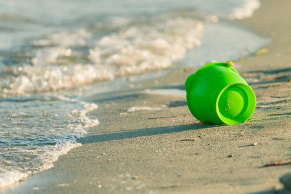 Speelgoed emmer op een strand in de buurt van de rand van de golven — Stockfoto