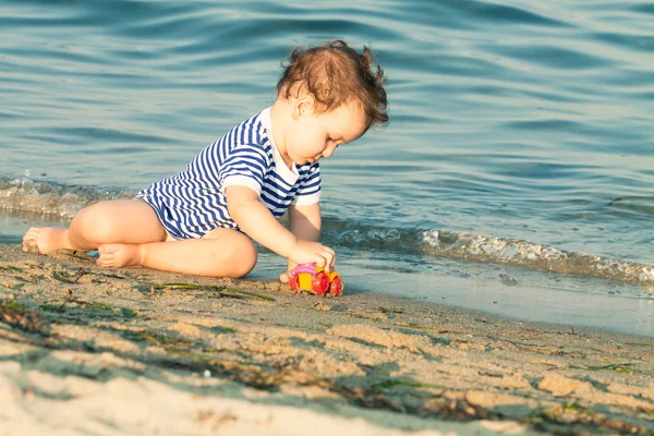 Adorable niño pequeño con camisa marinera jugando con un coche en el borde — Foto de Stock