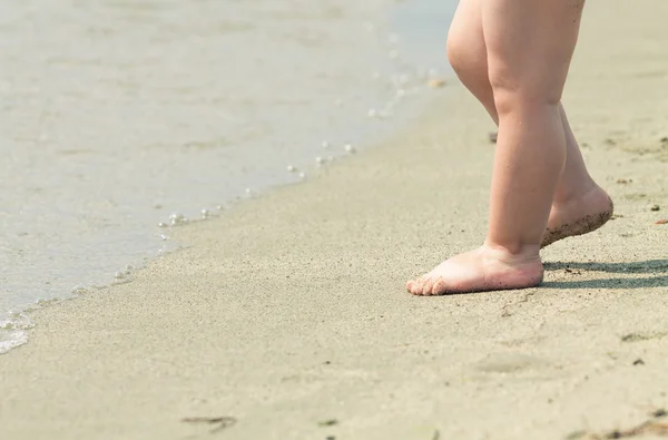 Yürümeye başlayan çocuk 's Feet bir plajda su kenarında yakın çekim. 