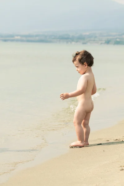 Lindo niño en una playa al borde del agua. Foto con unt — Foto de Stock