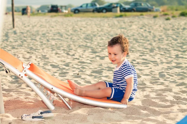 Playful toddler dressed as a sailor sitting on a tilted sunbed o — Stock Photo, Image