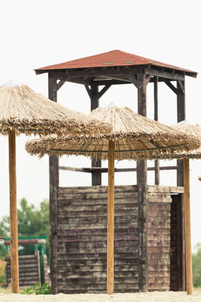 Hasır şemsiyeler ve bir plajda cankurtaran watchtower. Fotoğraf ile 