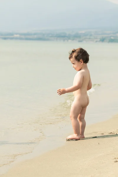 Schattig peuter op een strand aan de rand van het water. Foto met unt Stockfoto