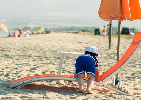 Zoete peuter verkleed als een zeeman klimmen op een zonnebank met uitzicht Stockafbeelding