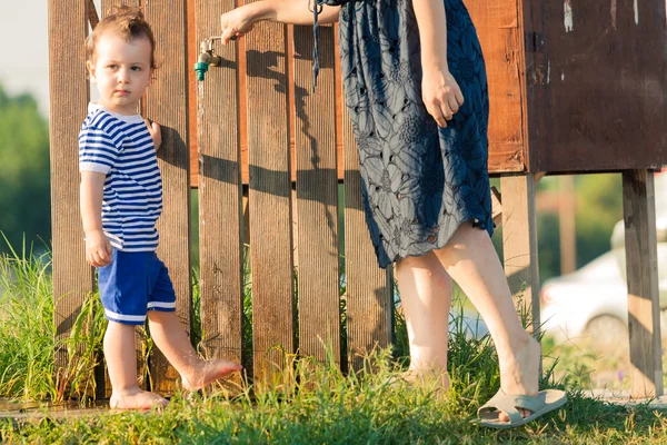 Toddler dressed as a sailor and his mother washing their feet af Royalty Free Stock Photos