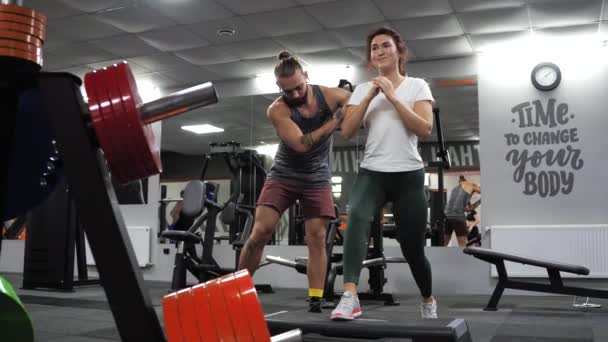 Aula de ginástica com um jovem treinador engraçado Uma aspirante a jovem lunges — Vídeo de Stock