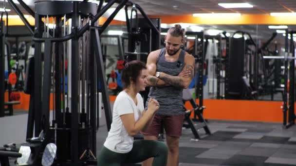 Aula de ginástica com um jovem treinador engraçado Uma aspirante a jovem lunges — Vídeo de Stock