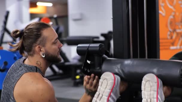 Gimnasio Lección con un hombre joven entrenador divertido Una mujer joven principiante sacude las piernas en el simulador — Vídeos de Stock