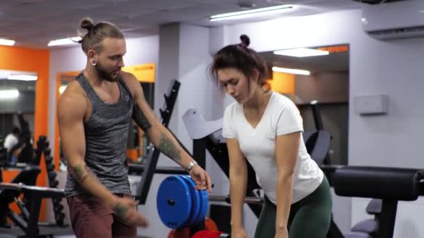Gimnasio Lección con hombre entrenador divertido Mujer joven principiante sacude la espalda hacia adelante doblas con pesas — Vídeos de Stock