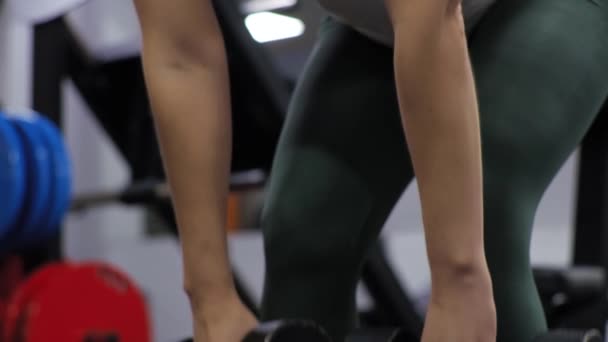 Cours de gymnastique avec entraîneur drôle homme Débutant jeune femme secoue son dos courbures avant avec haltères — Video