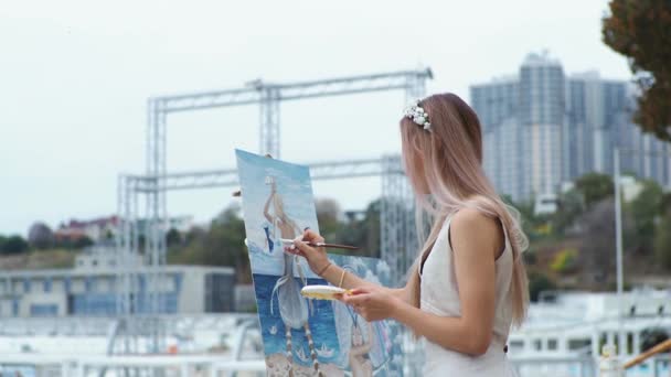 Jovem loira pinta um quadro na praia da cidade Ao ar livre — Vídeo de Stock