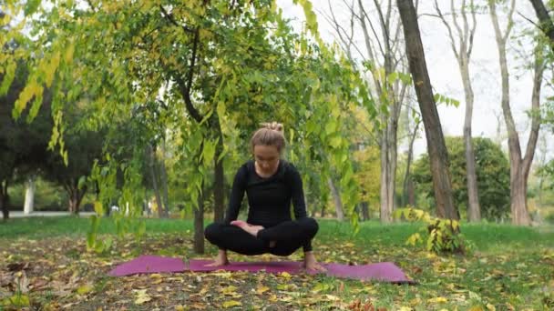 Jovem pratica ioga em um parque da cidade Na grama — Vídeo de Stock