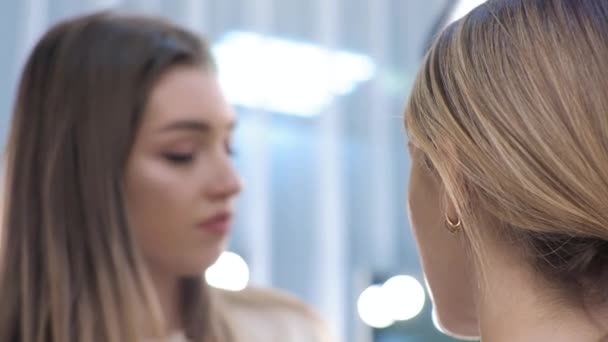 Young brunette woman make-up artist paints a blonde girl in a beauty salon Paints the eye contour — Stock Video