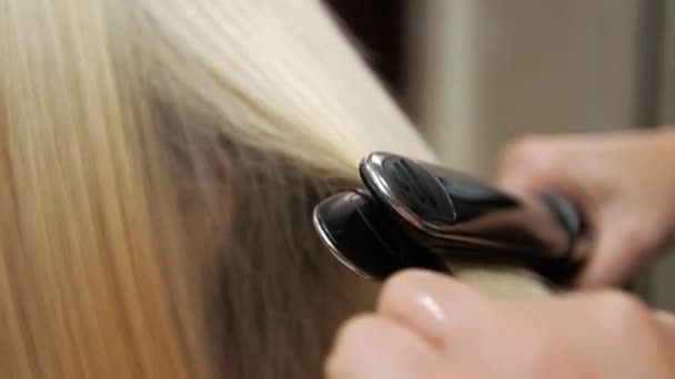 Jonge vrouw haar rechtgetrokken Blond in een schoonheidssalon — Stockvideo