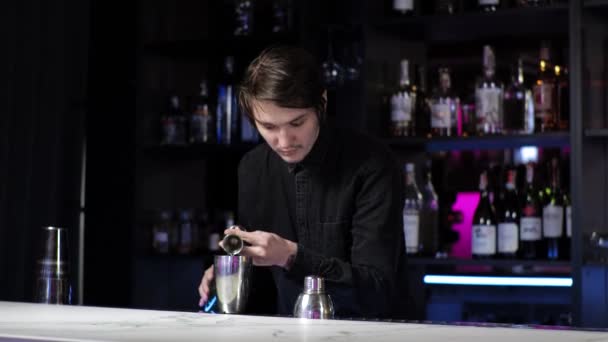 Ung novis bartender praktikant förbereda en cocktail vårdslös kille Blandar dryck och is i en shaker — Stockvideo