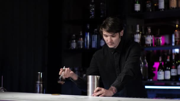 Jonge beginnende barman stagiaire het bereiden van een cocktail zorgeloze kerel mengt drinken en ijs in een shaker — Stockvideo