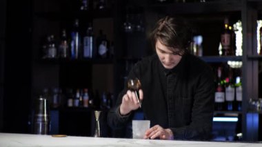 Genç acemi barmen stajyer kokteyl hazırlıyor dikkatsiz adam içkiyle buzu karıştırıyor.