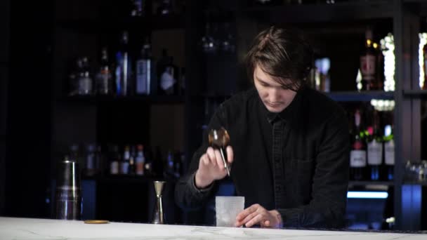 Ung novis bartender praktikant förbereda en cocktail vårdslös kille Blandar dryck och is i en shaker — Stockvideo