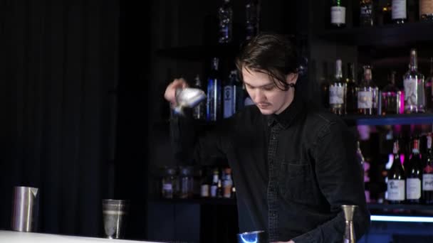 Jonge beginnende barman stagiaire het bereiden van een cocktail zorgeloze kerel mengt drinken en ijs in een shaker — Stockvideo