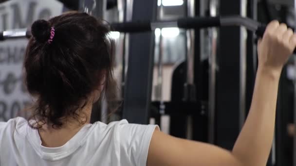 Siłownia Lekcja z młodym zabawnym trenerem mężczyzną Początkująca kobieta potrząsa plecami i ramionami na symulatorze — Wideo stockowe