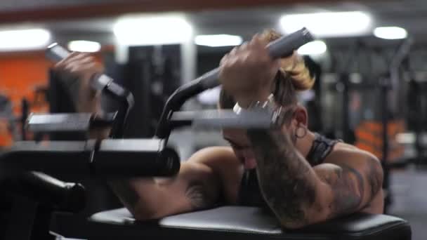 Junger Mann trainiert im Fitnessstudio. Schwerpunktmäßig schwingt der Bizeps der Arme im Simulator — Stockvideo