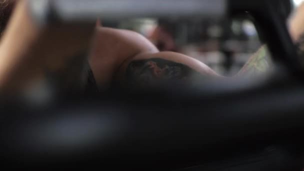 El joven trabaja en el gimnasio. Enfoque serio Mueve el bíceps de los brazos en el simulador — Vídeo de stock