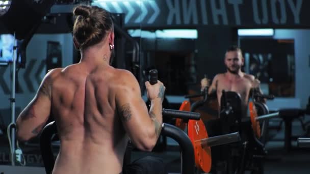 Ung man tränar i gymmet Seriöst fokuserad skakar axlar armar och bröst på simulatorn Push — Stockvideo