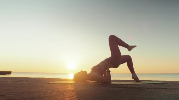 Mladá blondýna žena zapojená do jógy na pláži u moře pozadí východu slunce nebo západu slunce — Stock video