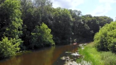 Yazın sakin orman nehri üzerindeki spor kanosunun insansız hava aracı görüntüsü