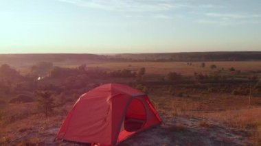 Hava aracı güneş doğarken tepedeki turist çadırına bakıyor.