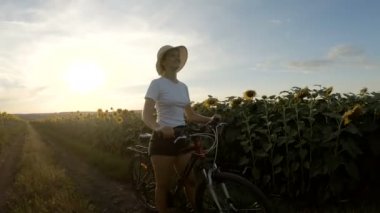 Ayçiçeği tarlaları arasında bisiklet süren sportif kız
