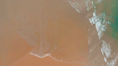 4k Havadan deniz dalgalarının görüntüsü sarı kumsalda kırılıyor