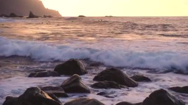 Okyanus dalgaları gün batımında kayalara çarpar Playa Benijo plajı, Tenerife, Kanarya