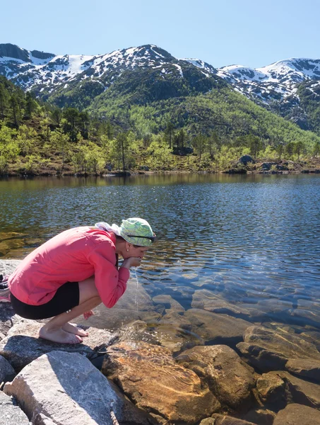 Donna sportiva beve acqua dal lago di montagna pulito — Foto Stock