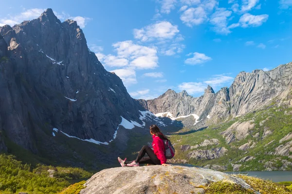 Mujer turista joven está sentado en piedra cerca de lago de montaña — Foto de Stock