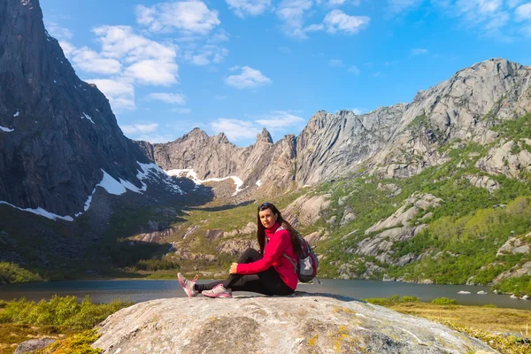 Mujer turista joven está sentado en piedra cerca de lago de montaña —  Fotos de Stock