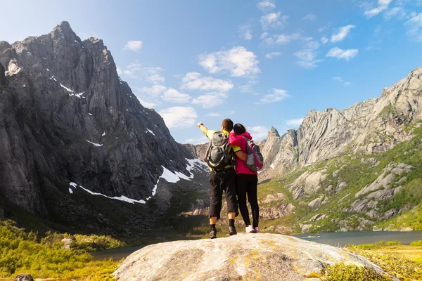 Unga turist par stående på sten nära mountain lake — Stockfoto