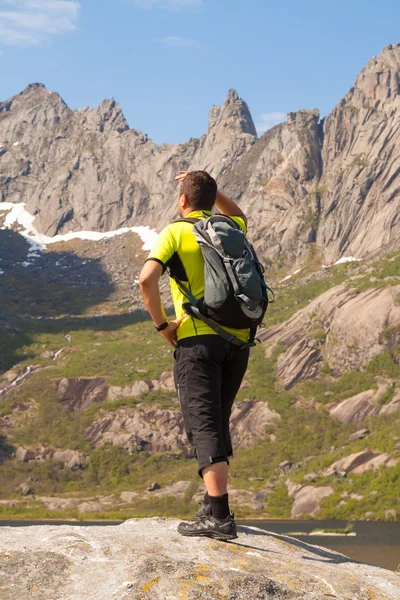 Young tourist man is standing  on stone near mountain lake — Stock Photo, Image