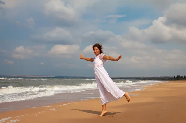 Mulher em um vestido branco na costa do oceano — Fotografia de Stock