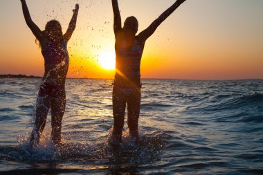 iki mutlu genç kız plajda atlama