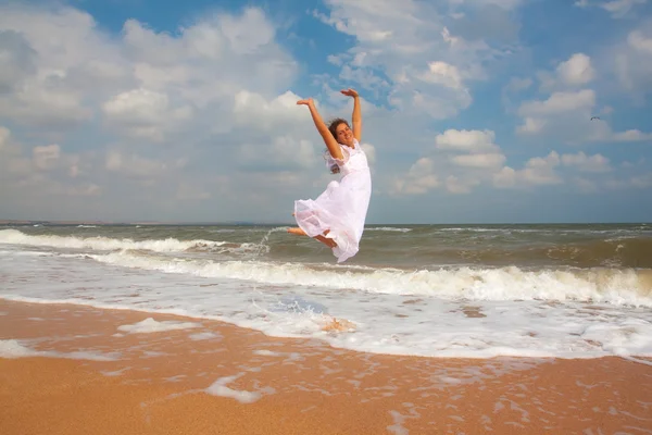 Fille heureuse sautant sur la plage ensoleillée — Photo